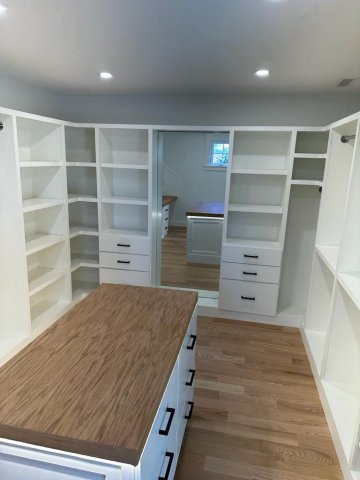 In the picture, a white closet with drawer and bars and custom island