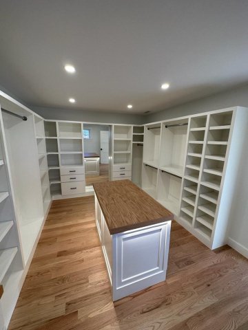 In the picture, a white closet with drawer and bars and custom island