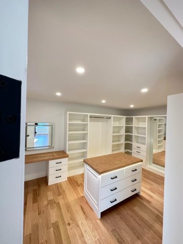 In the picture, a white closet with drawer, bars, custom island and vanity
